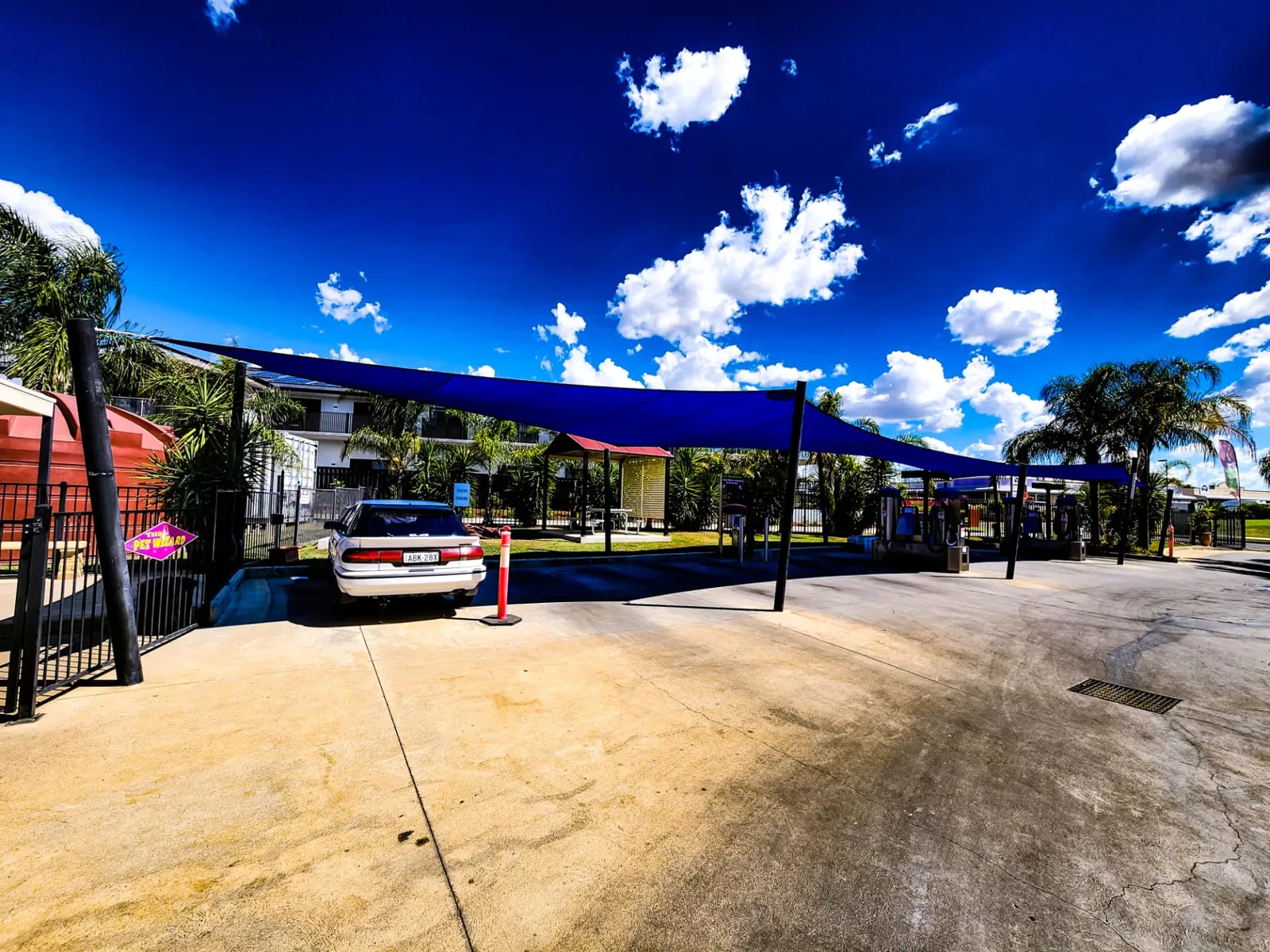 Blue commercial shade sails on steel posts covering car wash bays at a business site - New England Shade Sails, Tamworth