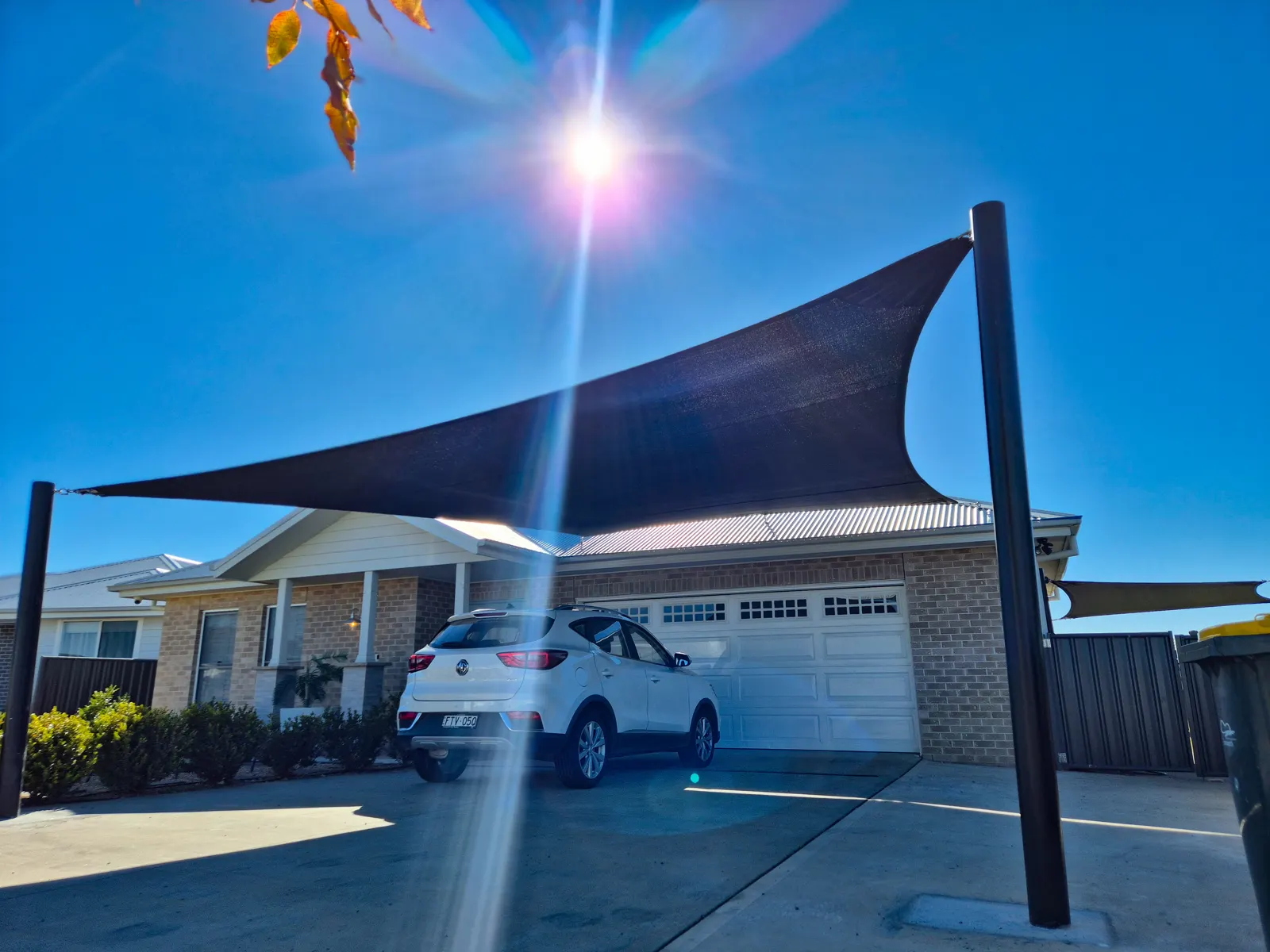 Black shade sail on dark steel posts shading a car on a home driveway - New England Shade Sails, Tamworth