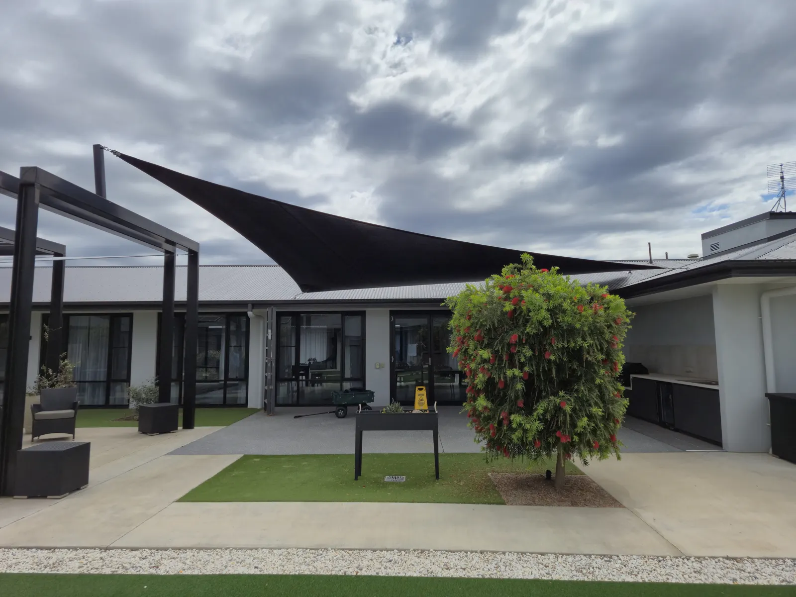 Black shade sail on a dark steel frame over a modern residential courtyard - New England Shade Sails, Tamworth
