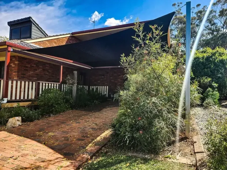 Charcoal shade sail above a brick patio and garden at a home - New England Shade Sails, Tamworth