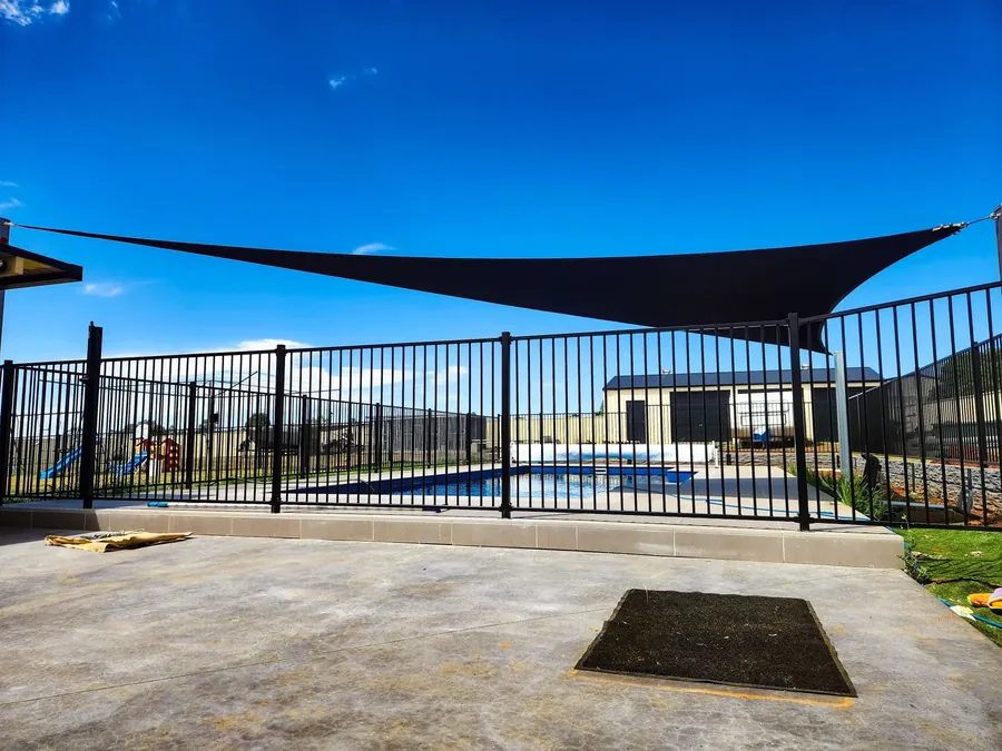 Charcoal shade sail beside a fenced swimming pool area - New England Shade Sails, Tamworth