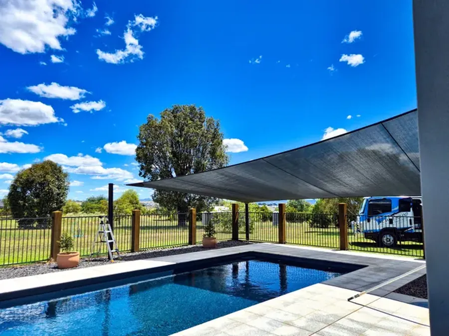 Charcoal shade sail shading a backyard swimming pool and paved surround - New England Shade Sails, Tamworth