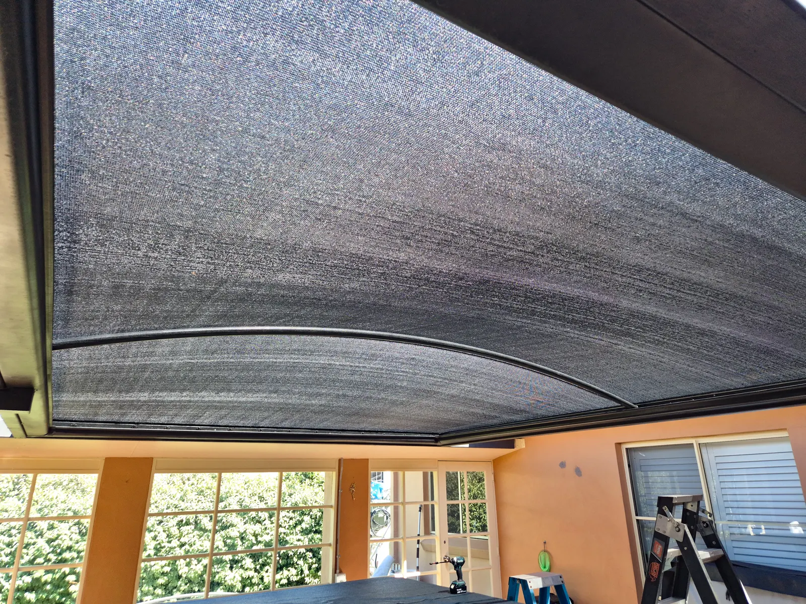 Underside of a tensioned charcoal shade sail covering a rendered home patio - New England Shade Sails, Tamworth