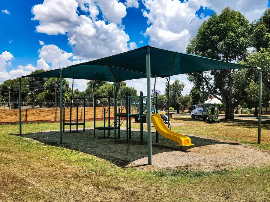 Green shade sail shading a playground slide and soft-fall surface - New England Shade Sails, Tamworth
