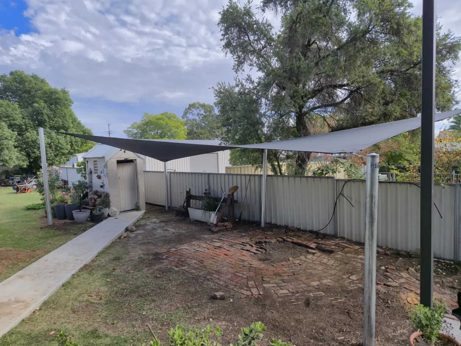 Grey shade sail on steel posts over a backyard garden beside a garden shed - New England Shade Sails, Tamworth