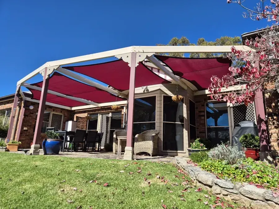 Maroon shade sails fitted over a timber pergola and outdoor dining area - New England Shade Sails, Tamworth