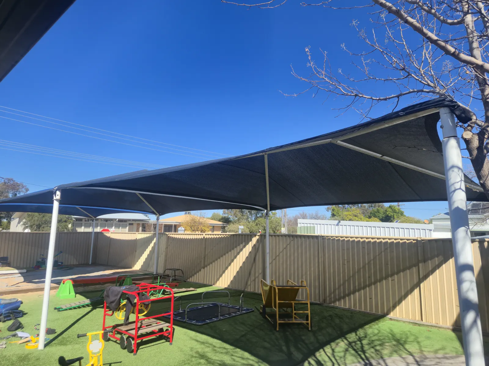 Navy shade structure on white posts covering a childcare playground with play equipment - New England Shade Sails, Tamworth
