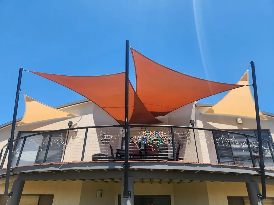 Orange shade sails shading a first-floor balcony at a country home - New England Shade Sails, Tamworth