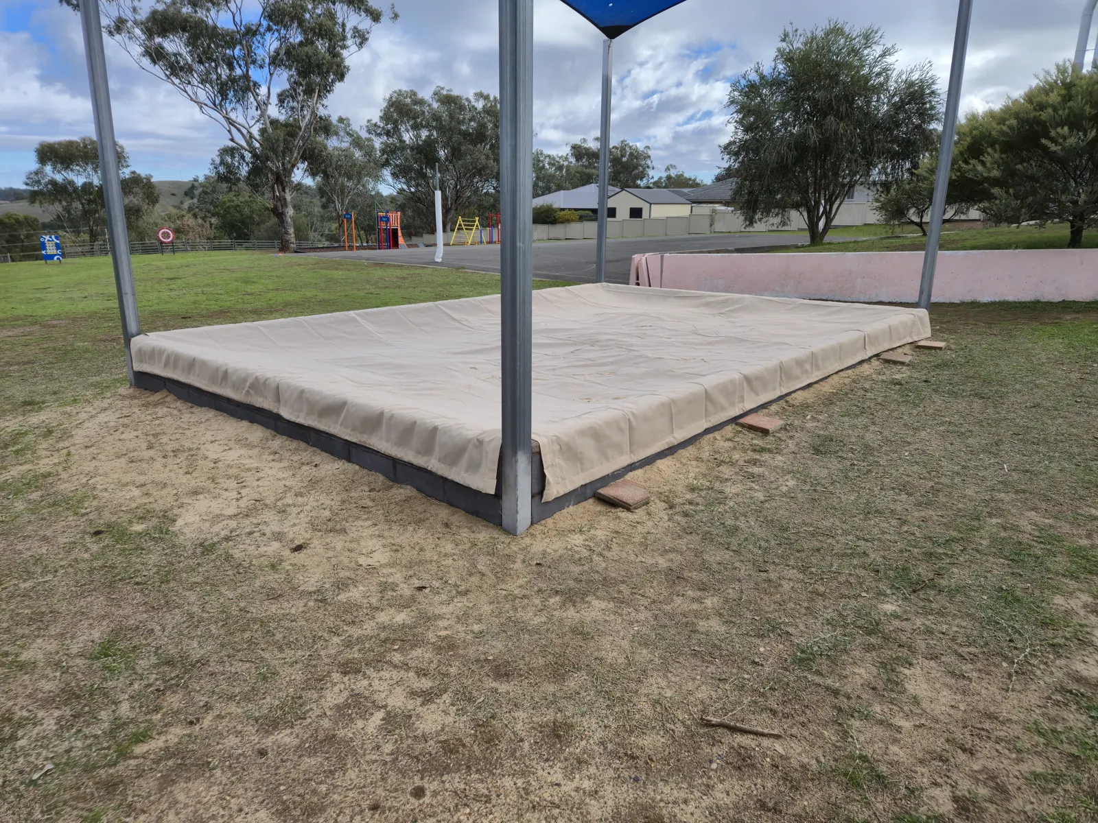 Sand coloured cover fitted over a large sandpit beneath a blue shade sail - New England Shade Sails, Tamworth