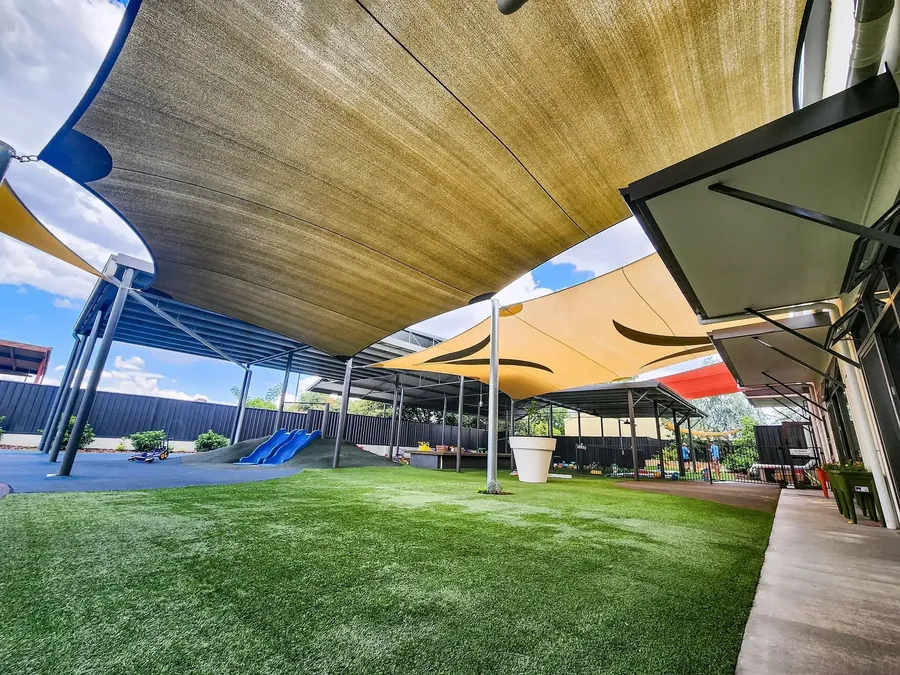 Underside of a sand-coloured shade sail above a school pool area - New England Shade Sails, Tamworth