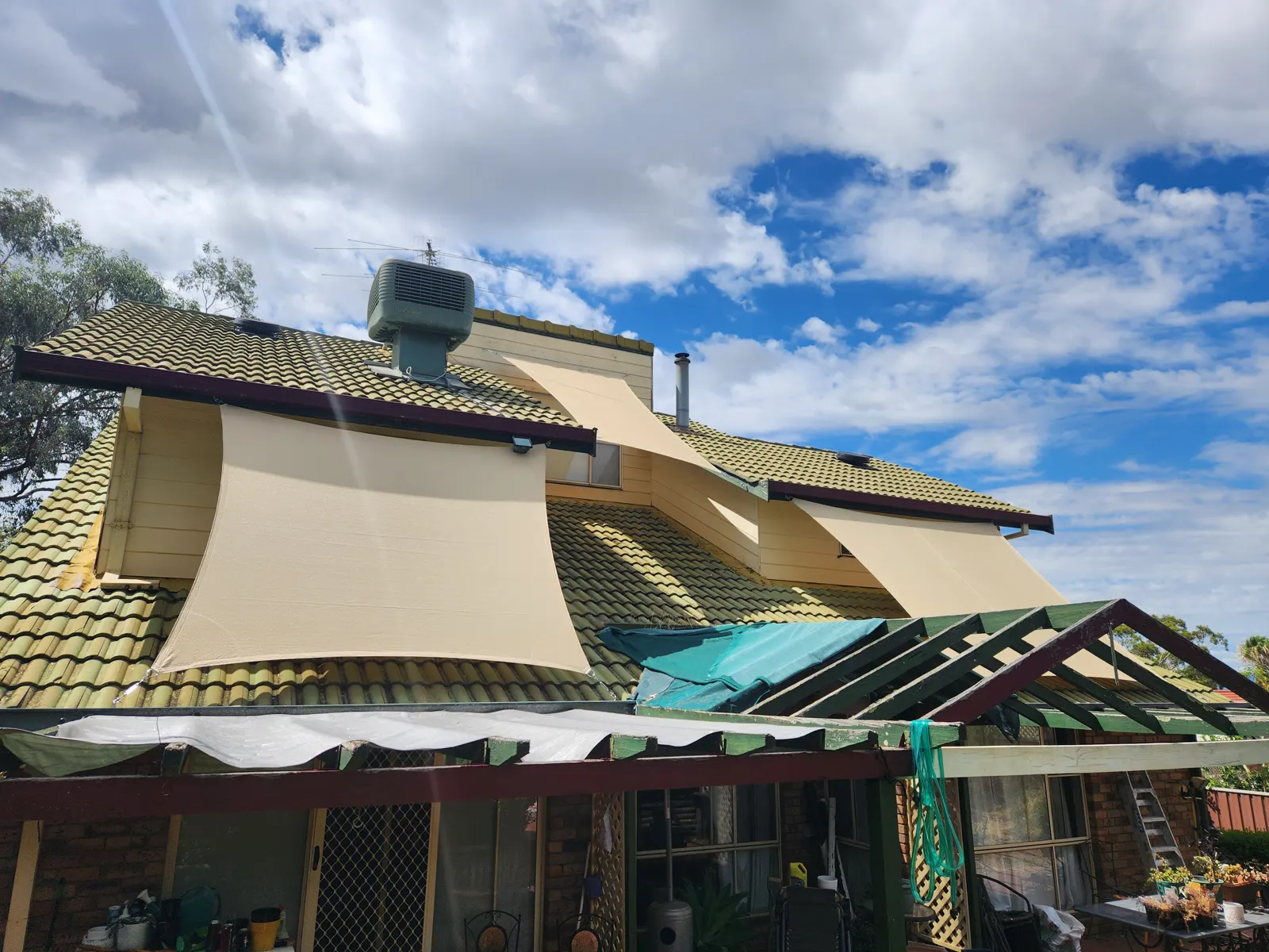 Sand coloured shade sails fixed over upstairs windows on a tiled roof home - New England Shade Sails, Tamworth