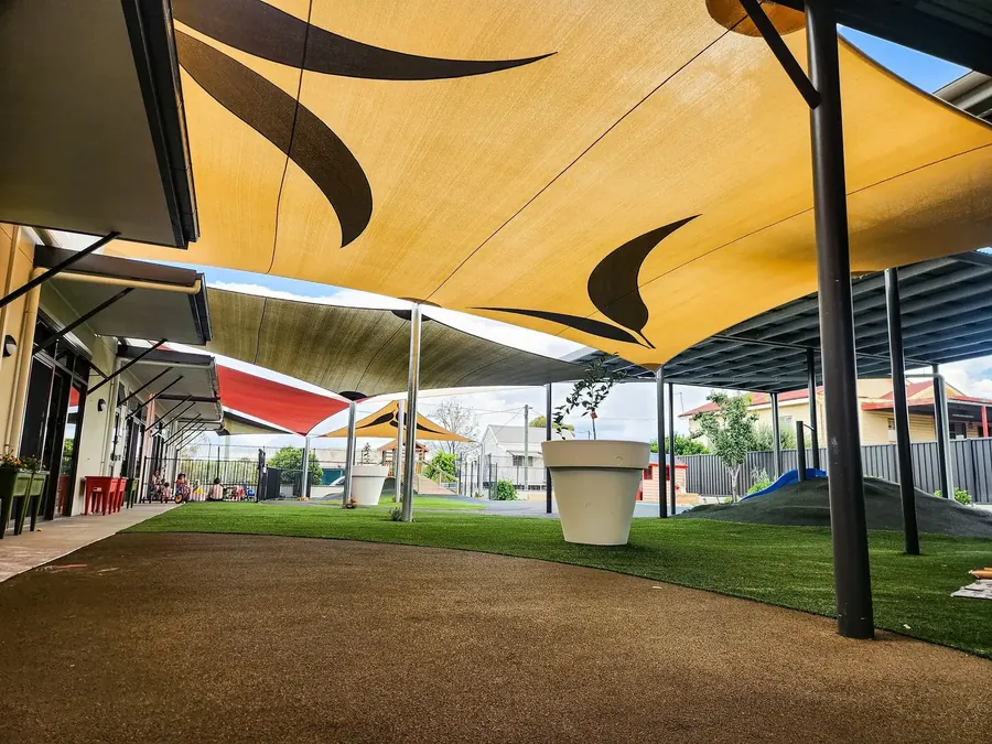 Sand-coloured shade sails shading a school walkway and play space - New England Shade Sails, Tamworth