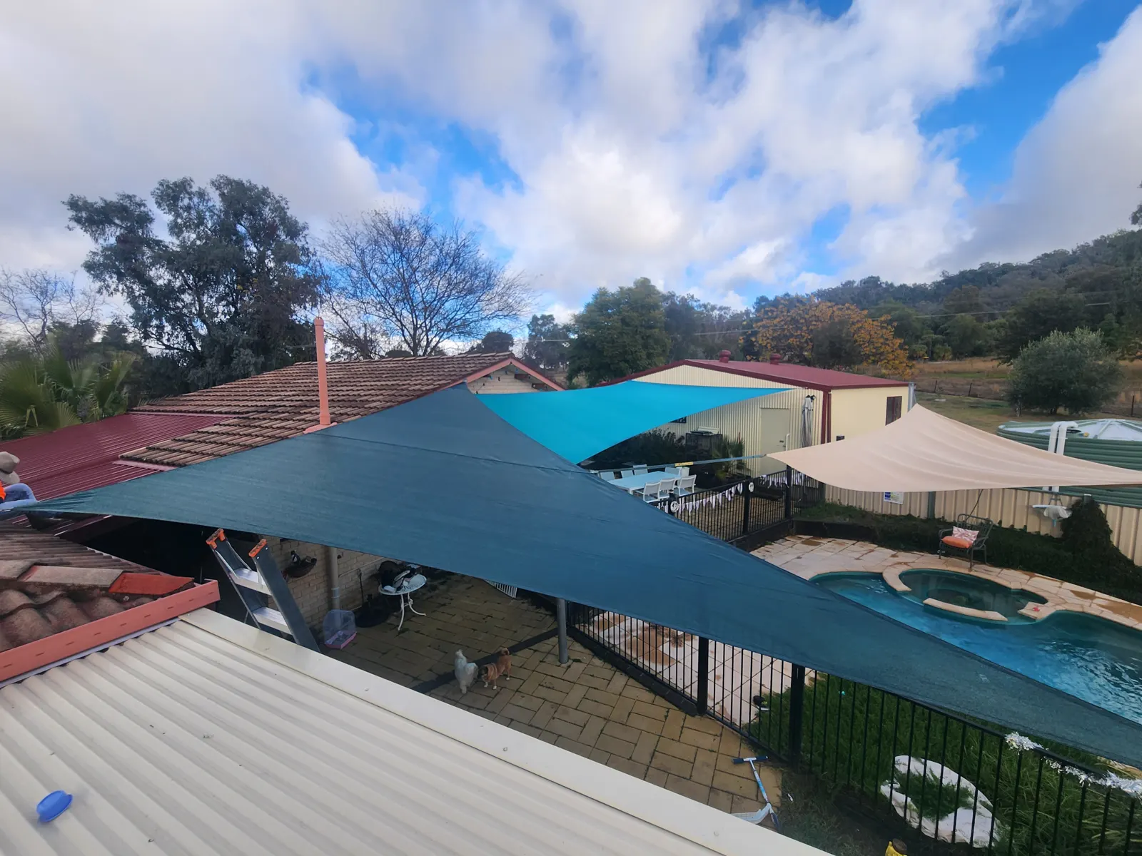 Teal and sand shade sails stretched over a backyard swimming pool and paved area - New England Shade Sails, Tamworth