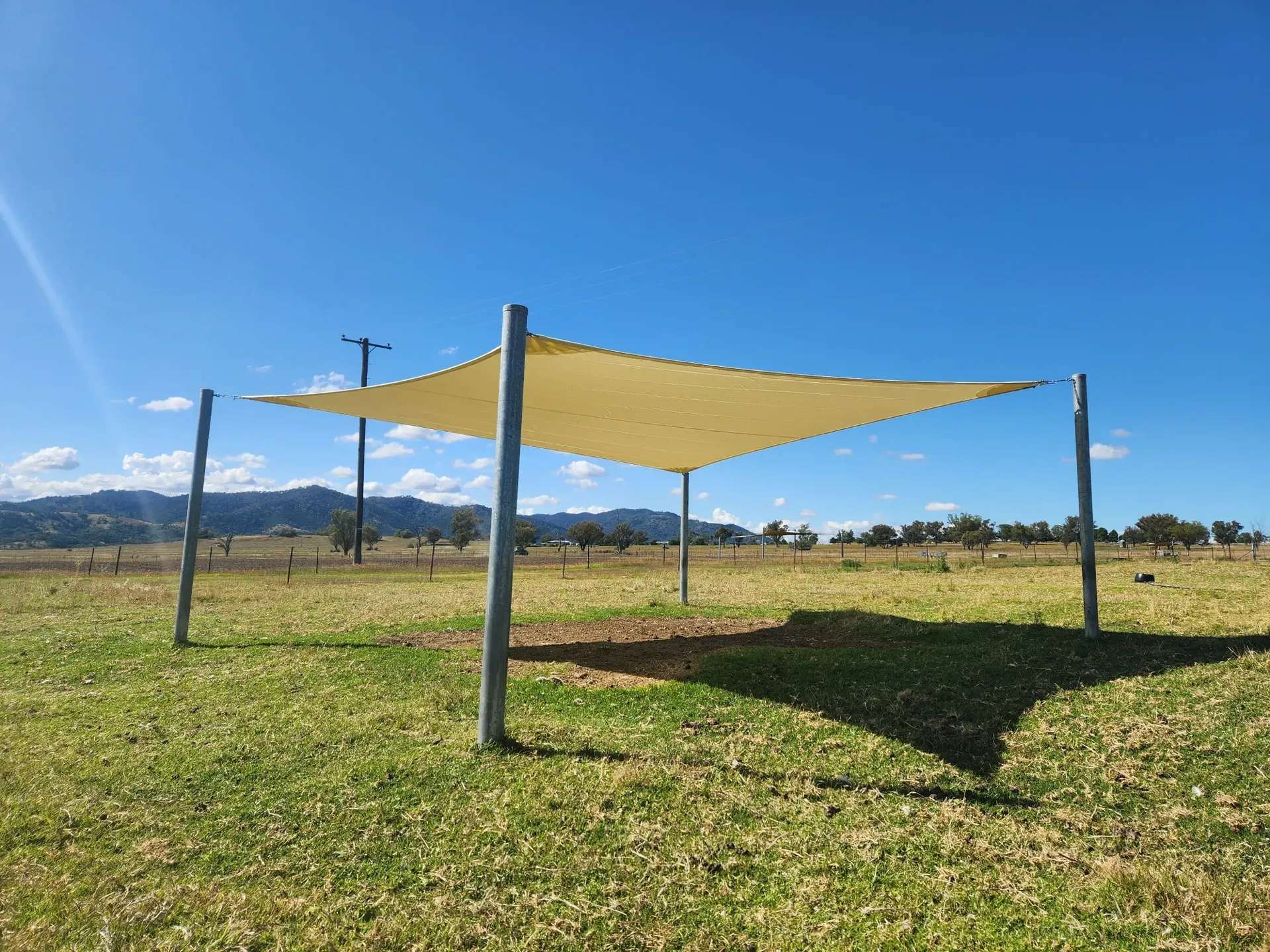 Large sand-coloured shade sail on steel posts at a New England rural property - New England Shade Sails, Tamworth