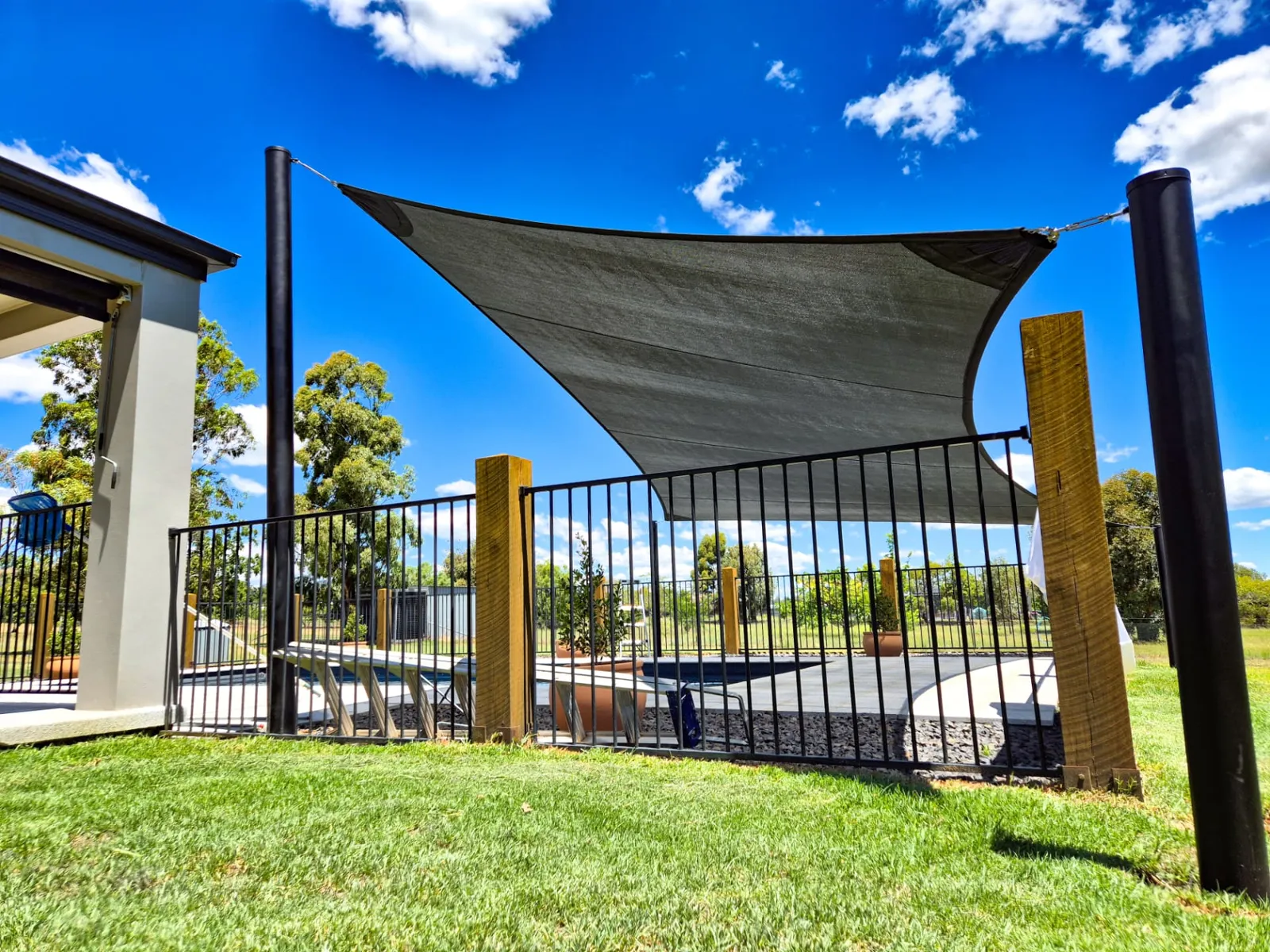Charcoal pool shade sail on black steel posts over a fenced backyard swimming pool - New England Shade Sails, Tamworth