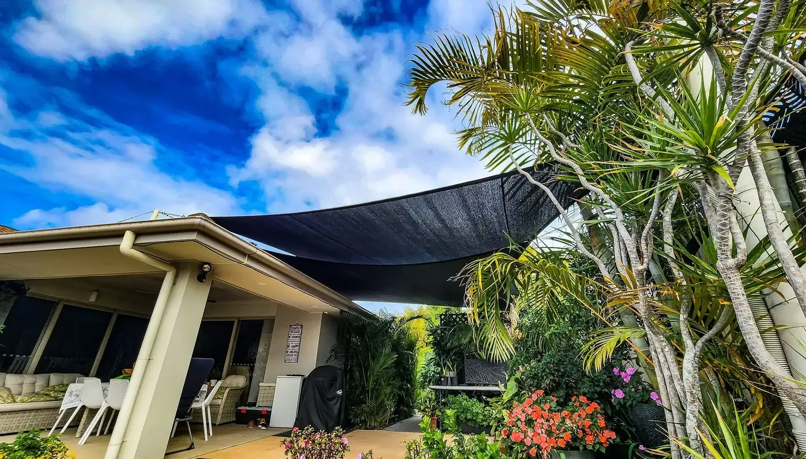 Residential shade sail shading a rear patio and lawn at a brick home - New England Shade Sails, Tamworth