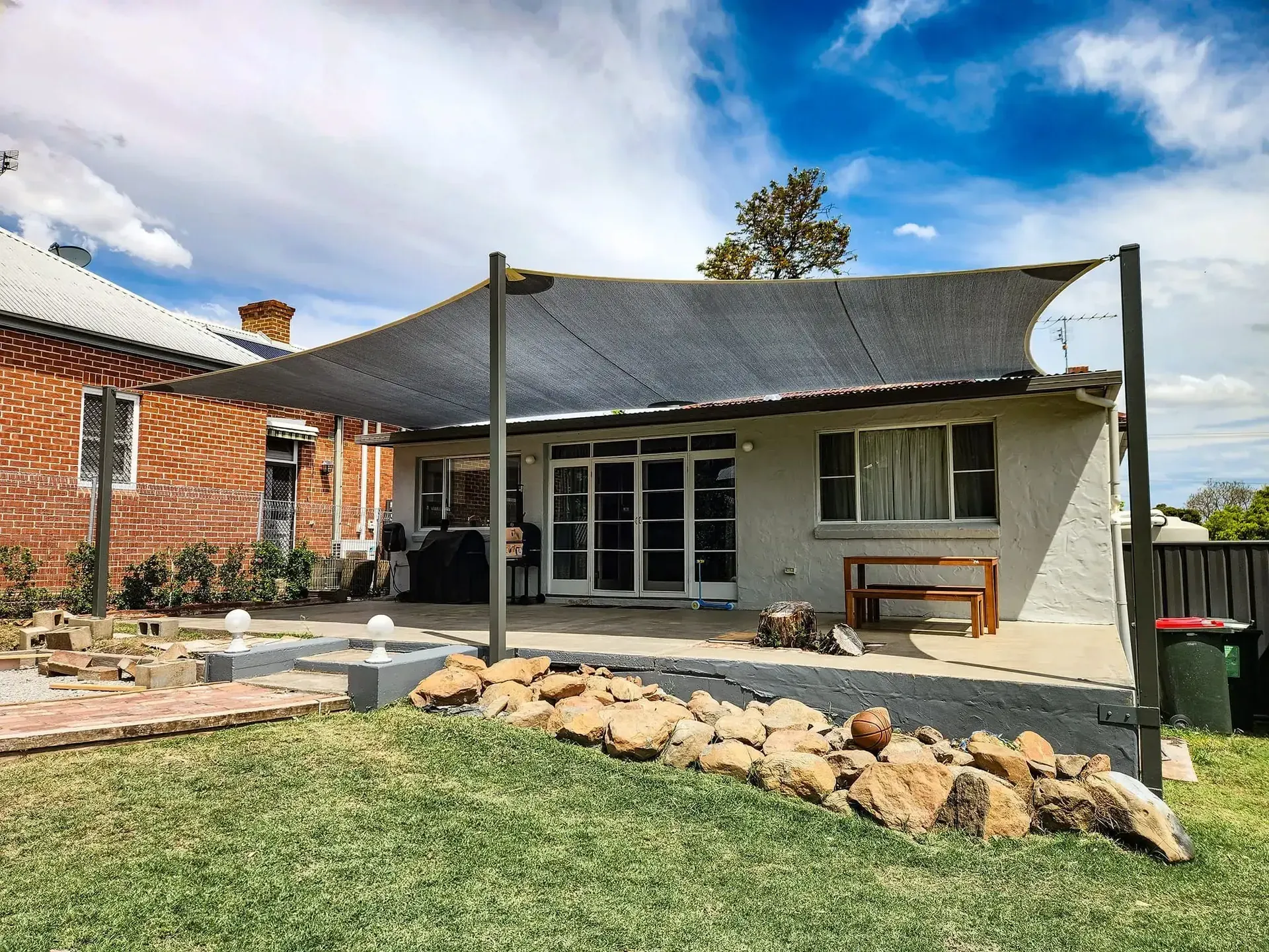 Charcoal residential shade sail over a tropical backyard entertaining area - New England Shade Sails, Tamworth