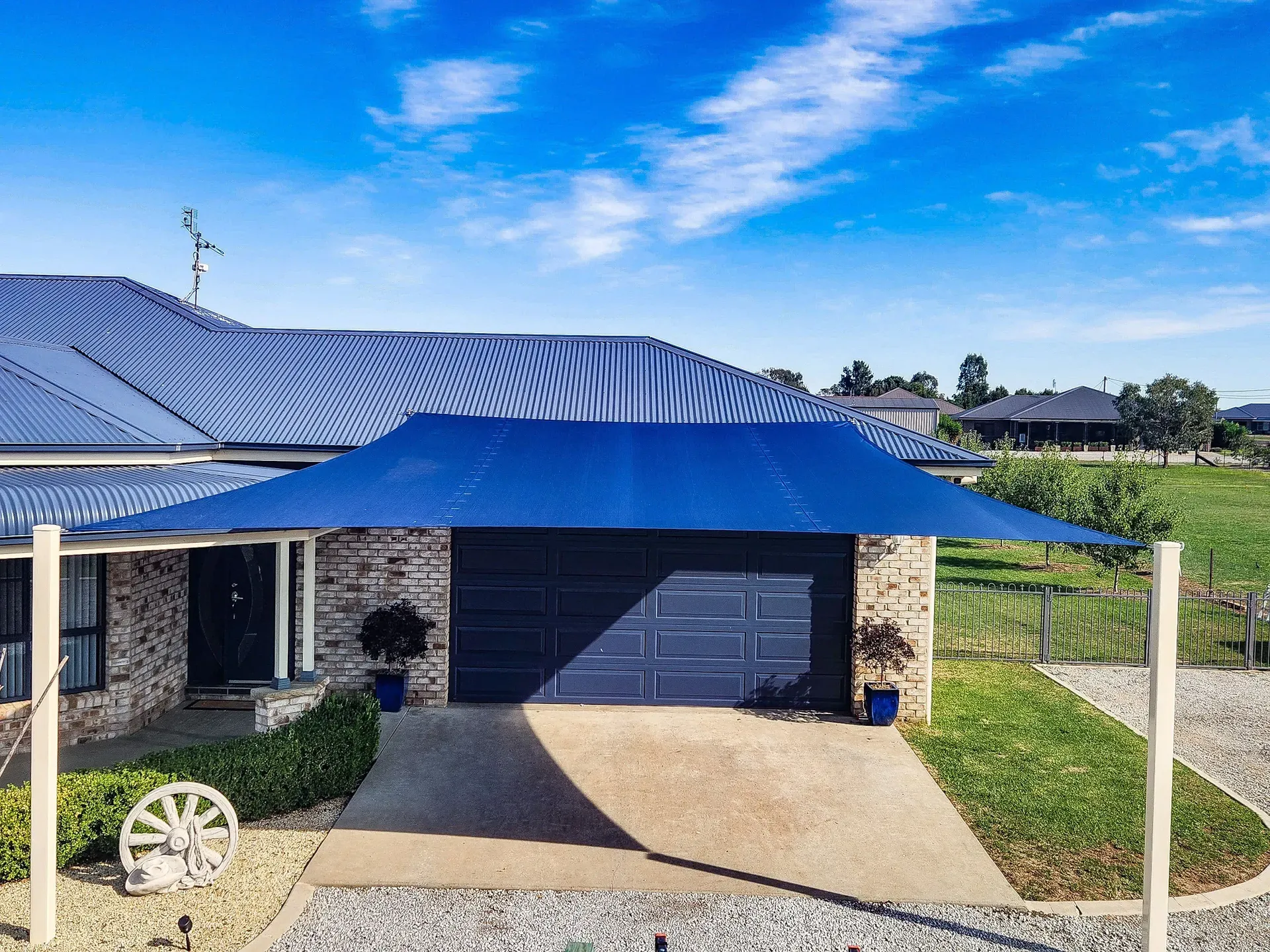 Blue shade sail over a garage driveway at a brick home in Gunnedah - New England Shade Sails, Tamworth